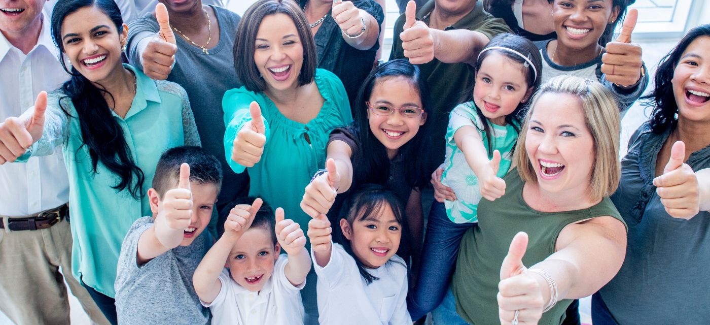 Large group of diverse people giving a thumbs up to the camera.